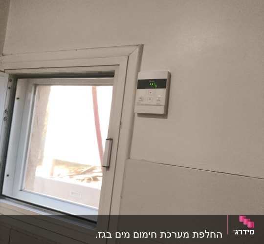 תרמוסטט דיגיטלי מותקן על קיר ליד חלון